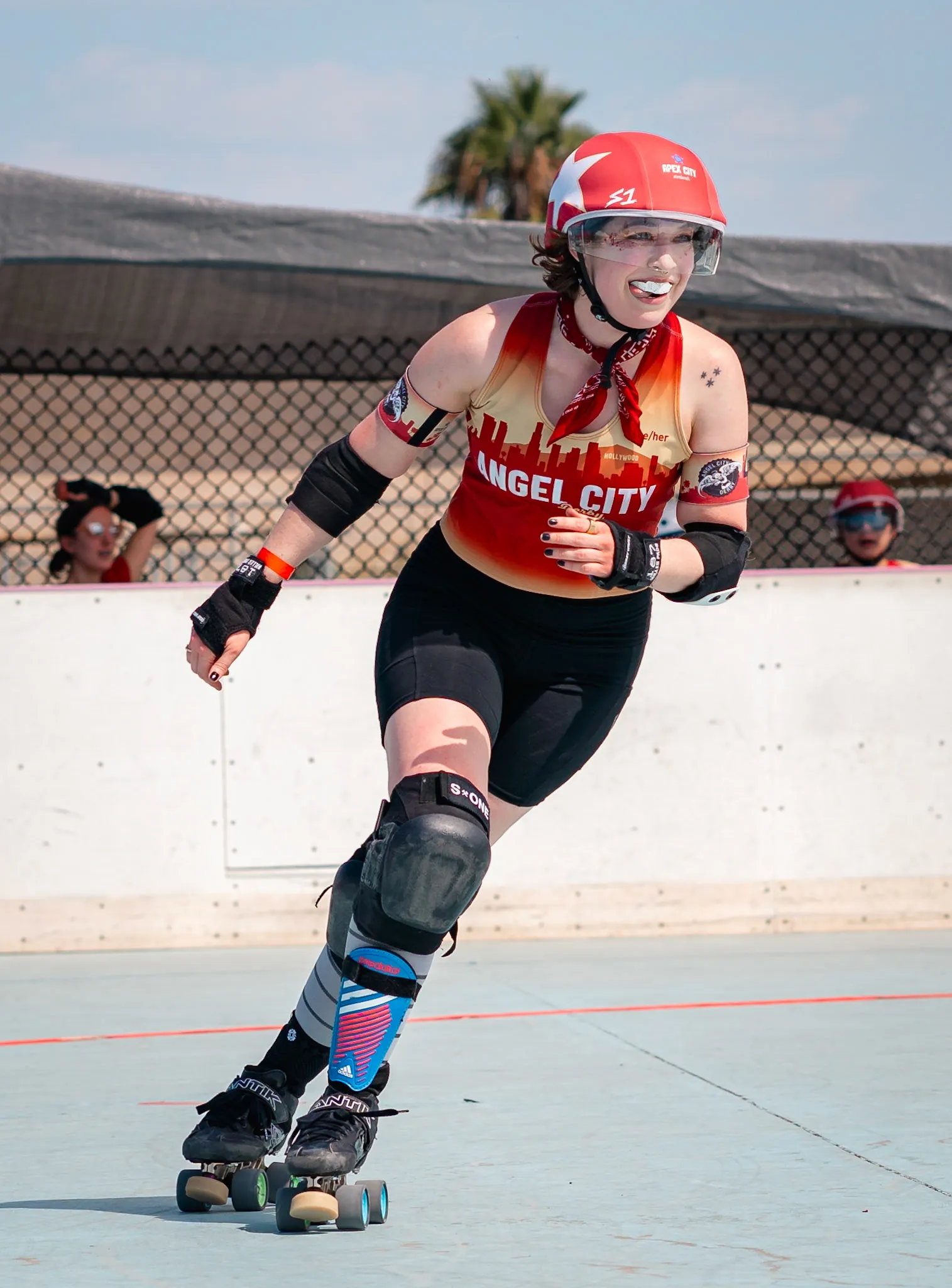 I'm rounding the corner of a roller derby track. I have a mischievous grin.
